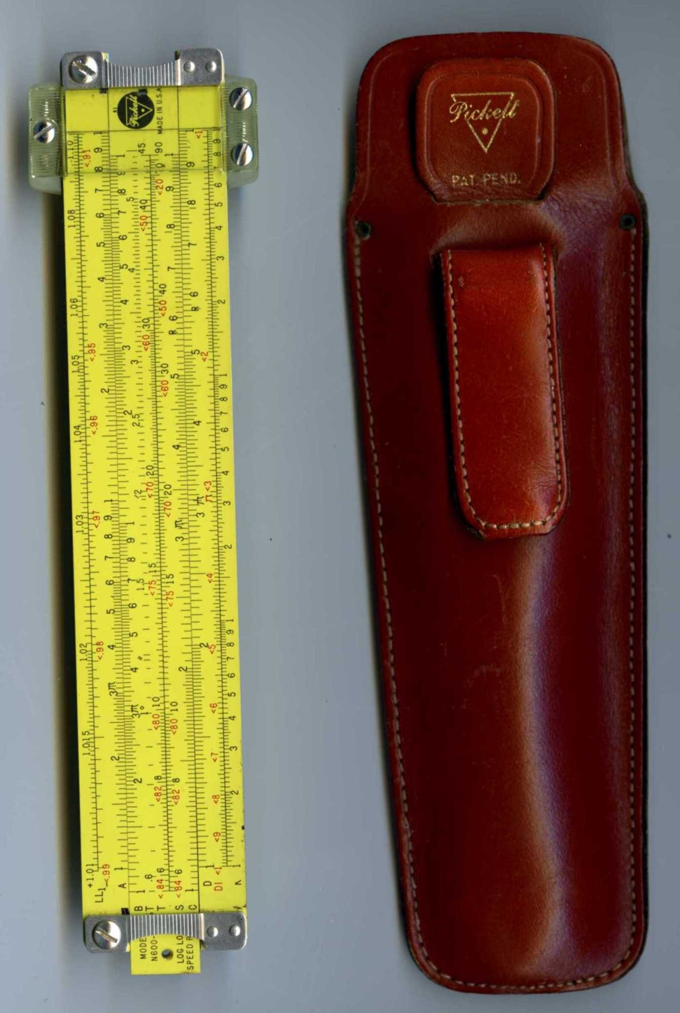 Figure 5 — A yellow Pickett N600-ES six-inch slide rule beside its red-brown leather holster with a belt loop and a gold Pickett triangle logo marked PAT. PEND.