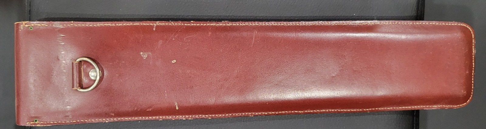 Figure 3 — The back of my CIE leather case: plain burgundy leather with stitched edges and a metal D-ring on a leather tab near one end.
